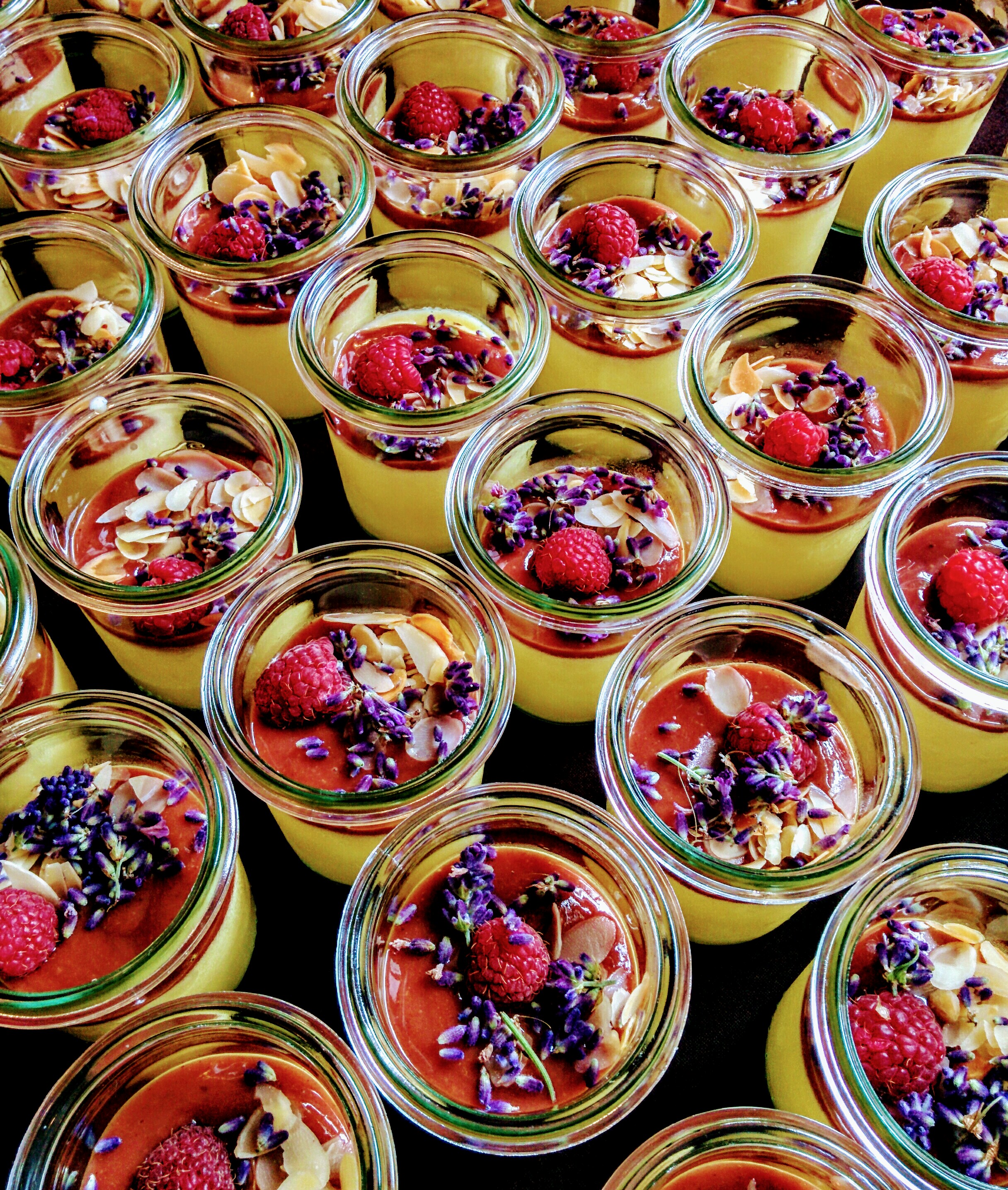 Kolorowe zdjęcie współczesne. Przedstawia stół na którym leżą słoiki z galaretką przybrane kolorowymi owocami. 