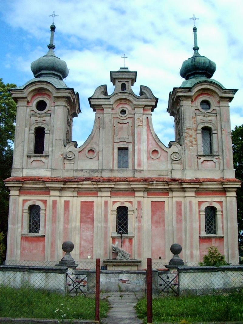 Kolorowe zdjęcie współczesne. Przedstawia fasadę kościoła z dwiema wieżami. Fasada jest zniszczona. Jest to kościół w Szewnej, stan w 2005 r.