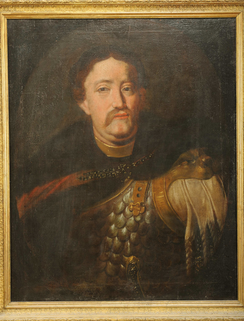 Portret olejny króla Jana III Sobieskiego oprawiony w złotą, ozdobną ramę. Król Jan przedstawiony jest w zbroi. Na ramiona ma narzucony płaszcz z futrzanym kołnierzem, zapięty ozdobną broszą. Król ma poważny wyraz twarzy.
