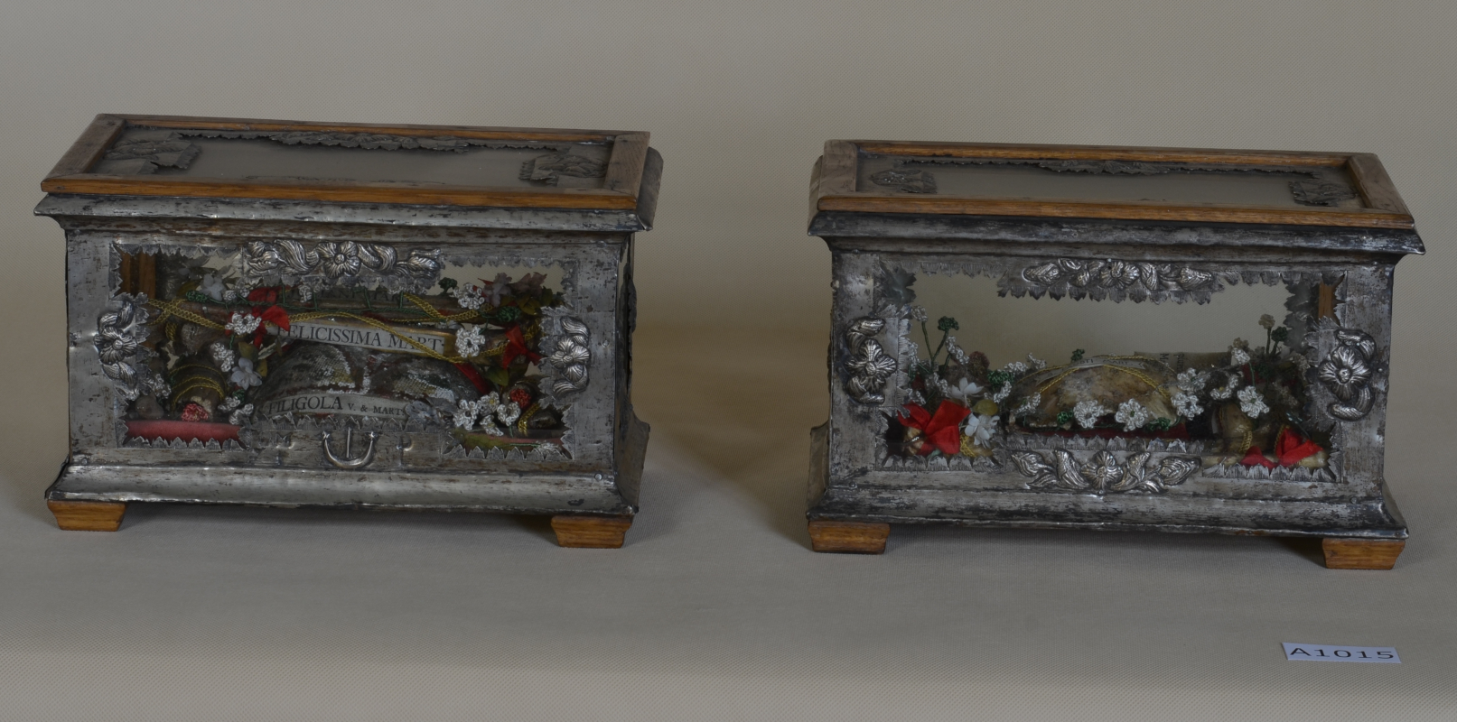 Zdjęcie przedstawia dwie szkatułki srebrne z elementami drewnianymi w postaci nóżek i nakrycia na wiekach. Boki szkatułek dekorowane są elementami roślinnymi.