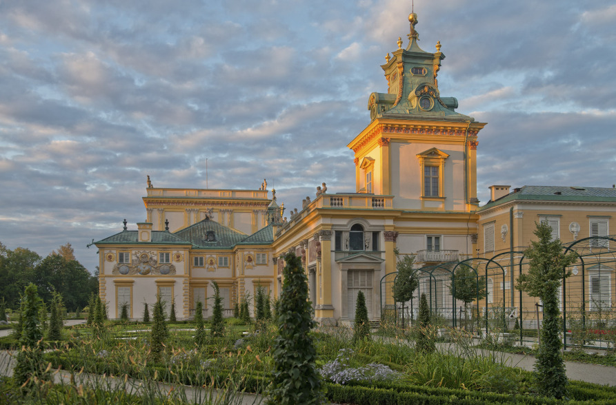 Contemporary colour photo. This shows a view of the Palace with the tower, in bright yellow. It is the Palace in Wilanów. In the foreground is the Garden. 