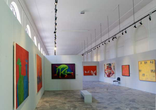 Kolorowe zdjęcie przedstawia wnętrze galerii współczesnej. Na ścianach wiszą dzieła sztuki.