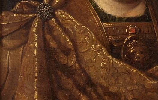 Zbliżenie na fragment obrazu olejnego "Jan III Sobieski w wieńcu laurowym". Połyskująca złotem szata spięta broszą z kamieniami szlachetnymi. Na wysokości piersi króla wizerunek Gorogony.