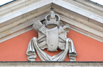 Kolorowa fotografia współczesna. Przedstawia fasadę kościoła kapucynów w Warszawie i zbliżenie na herb w przyczółku kościoła. 