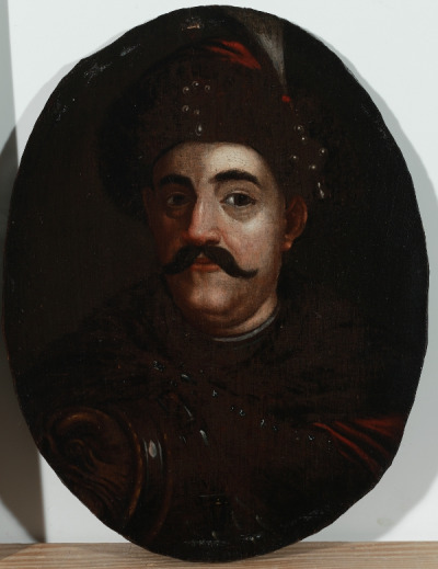 
Portret króla Jana III. Interesujący portret królewski ukazuje monarchę w popiersiu ¾ w lewo, w futrzanej czapce z klejnotem i piórem, w karacenie i delii spiętej podłużną zaponą na prawym ramieniu. 