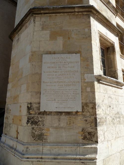 Zdjęcie współczesne. Przedstawia płytę zamontowaną na kamiennej ścianie starego budynku pałacowego. Na płycie napis w języku francuskim. Jest to tablica pamiatkowa w Palais Ducal. 