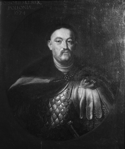 Obraz olejny. Przedstawia realistyczny portret Jana III Sobieskiego. Król ubrany w zbroję, z płaszczem na ramionach. Wizerunek namalowany jest realistycznie z dbałością o każdy szczegół.