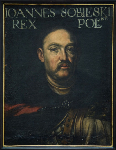 Portret Jana III Sobieskiego. Na górze obrazu napis: IOANNES SOBIESKI REX POL. Obraz przedstawia realistyczny portret Jana III Sobieskiego. Król ubrany w zbroję, z płaszczem na ramionach. Wizerunek namalowany jest realistycznie z dbałością o każdy szczegół.