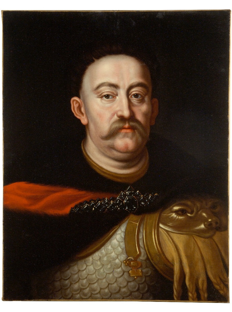 Portret Jana III Sobieskiego. Olej na płótnie. Obraz przedstawia króla namalowanego w sposób realiztyczny z dbałością o każdy, najmniejszy szczegół. Król ubrany w zbroję i dalię spiętą broszą. Tło obrazu ciemne. 