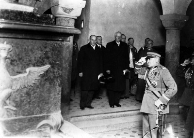 Czarno-białe zdjęcie archiwalne. Dokumentuje złożenie hołdu w krypcie króla Jana III Sobieskiego na Wawelu. Na zdjęciu widoczni są m.in.: marszałek Józef Piłsudski. Jest to zdjęcie wykonane z okazji 250 rocznica Odsieczy Wiedeńskiej - Święto Kawalerii w Krakowie.