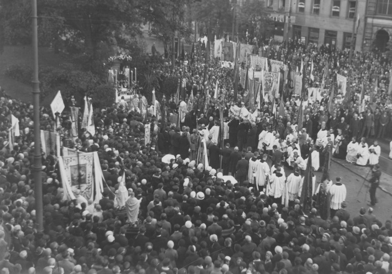 Czarno-białe zdjęcie archiwalne. Dokumentuje procesję z okazji 250 rocznicy bitwy pod Wiedniem, która przeszła z kościoła oo. Kapucynów przy ul. Miodowej do figury Najświętszej Maryi Panny Zwycięskiej na Krakowskim Przedmieściu, ufundowanej przez króla Jana III - również w rocznicę Odsieczy. Zdjęcia ze zbiorów i dzięki uprzejmości Narodowego Archiwum Cyfrowego.