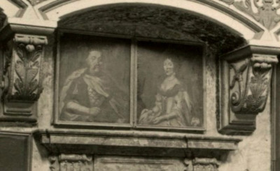 Stare zdjęcie z widokiem wnętrze pałacu w Podhorcach. Dekoracja zamku zawierała wiele pamiątek po rodzinie Sobieskich, które uzupełniane były wtórnie przez kolejnego właściciela, Wacława Rzewuskiego. Na zdjęciu kaplicy pałacowej z 1909 widoczne są również dwa portrety pary królewskiej zawieszone nad wejściem.
