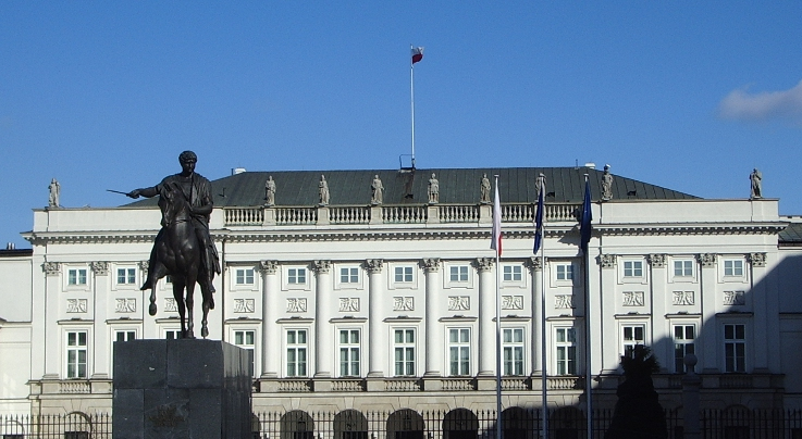 Kolorowe zdjęcie współczesne. Przedstawia dawny Pałac Radziwiłłów w Warszawie, obecnie Pałac Prezydencki w Warszawie. Przed budynkiem pomnik konny na postumencie. 
