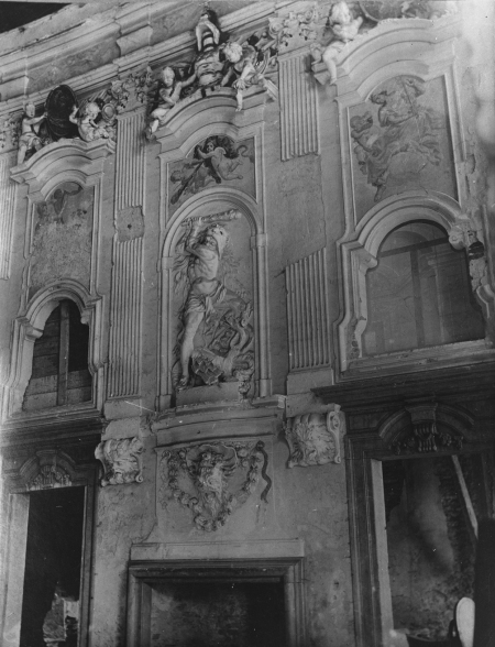 Czarno-białe zdjęcie wnętrza pałacu. Nad portalem przedstawienie Herkulesa. Jest to stara dekoracja pałacu w Łubnicach.