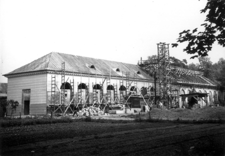 Czarno białe zdjęcie archiwalne. Przedstawia widok na południowo-zachodnią stronę odbudowywanej oranżerii w Wilanowie w 1957 roku. 