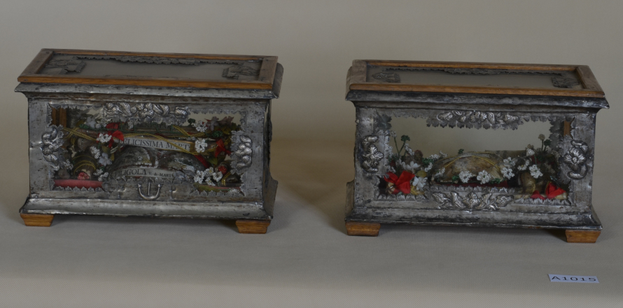 Zdjęcie przedstawia dwie szkatułki srebrne z elementami drewnianymi w postaci nóżek i nakrycia na wiekach. Boki szkatułek dekorowane są elementami roślinnymi.