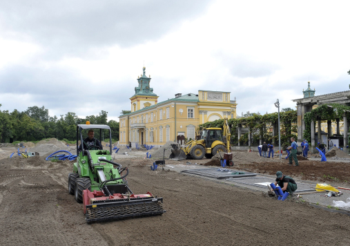 Ogród w trakcie prac rewitalizacyjnych. Pracownicy porządkują teren ogrodu. Używają do tego specjalistycznych traktorów