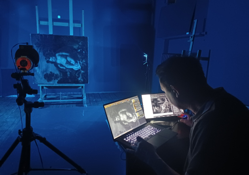 Mężczyzna bada obraz za pomoc specjalistycznej aparatury. Wyniki badań odczytuje na ekranie komputera.