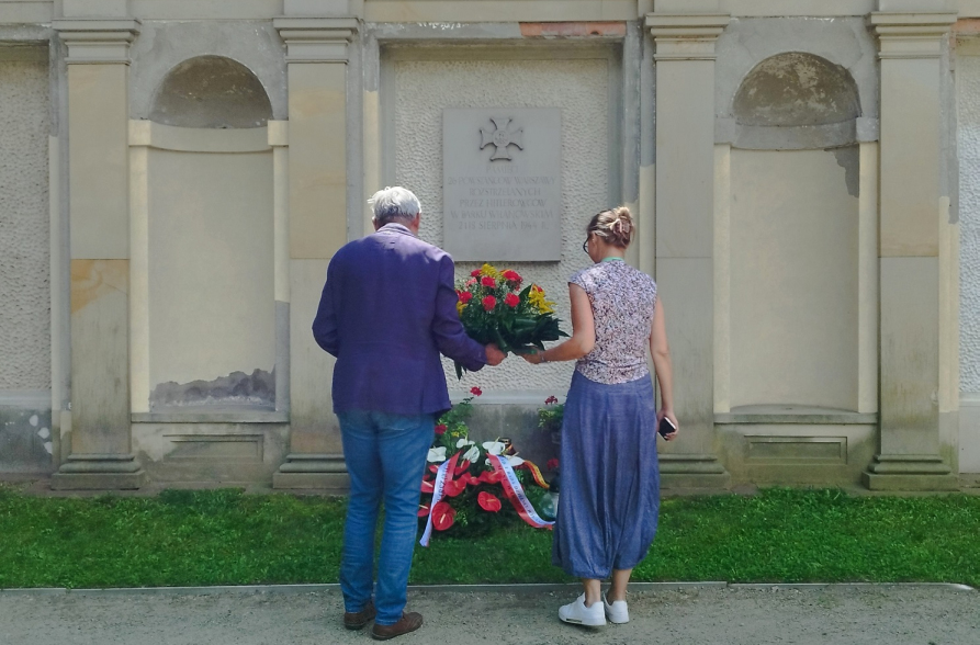 Mężczyzna i kobieta składają wieniec pod pamiątkową tablicą